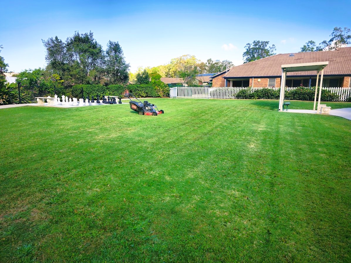A mown lawn with a ride-on mower in the distance