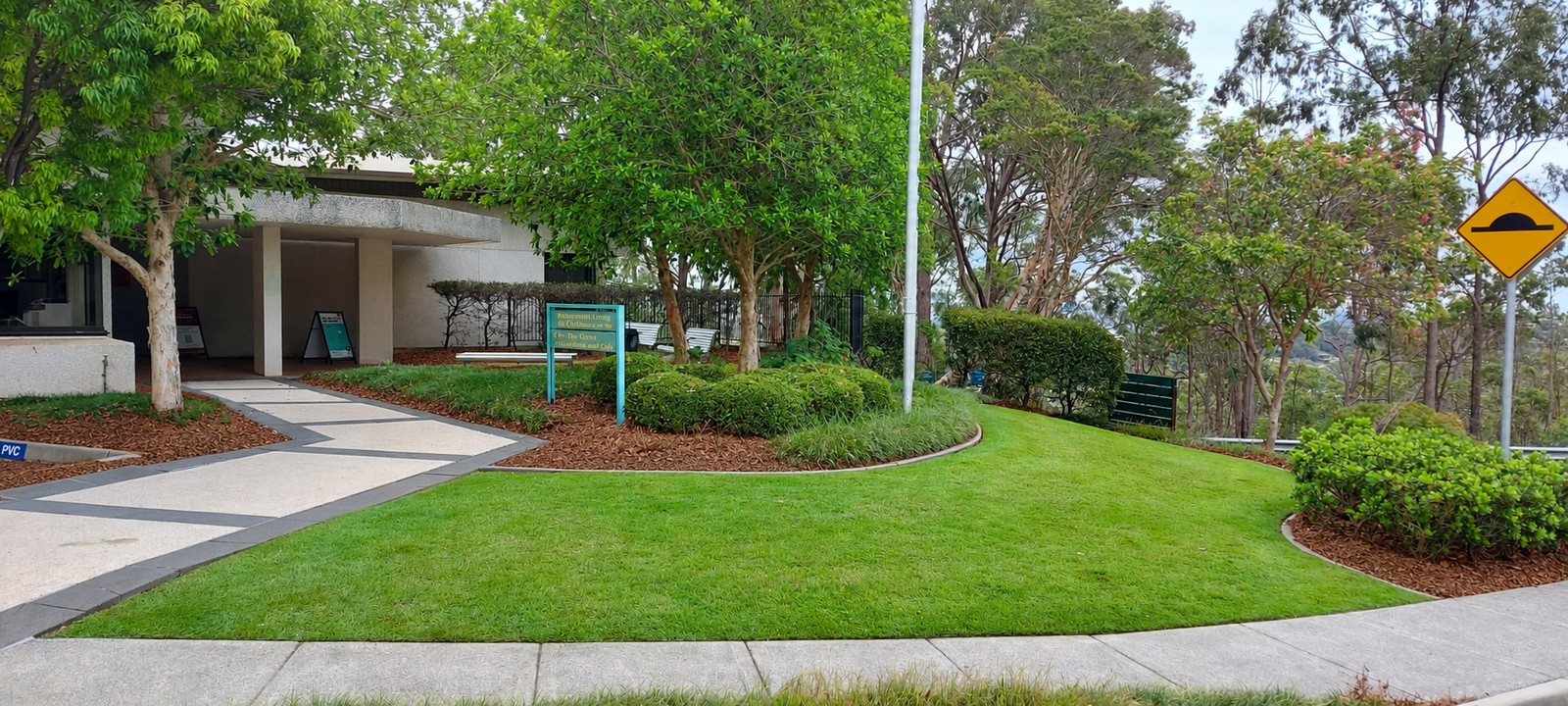 Neatly edged lawn and pine bark garden beds beside the village entrance